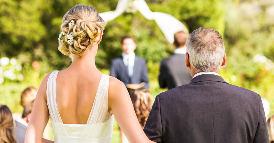 A father walks a bride down the aisle. 