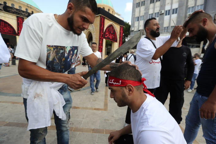 A Lebanese Shiite man is about to cut the head of his friend with a sword during a ritual on the holy Muslim Shiitte day of Ashoura, in the southern market town of Nabatiyeh, Lebanon, Tuesday, Aug. 9, 2022. Ashoura is the annual Shiite commemoration marking the death of Imam Hussein, the grandson of the Prophet Muhammad, at the Battle of Karbala in present-day Iraq in the 7th century. (AP Photo/Mohammed Zaatari)
