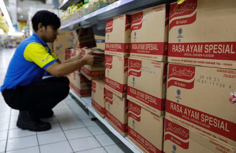 A worker arranges boxes of Indomie Special Chicken Flavour instant noodles, at a supermarket in Jakarta