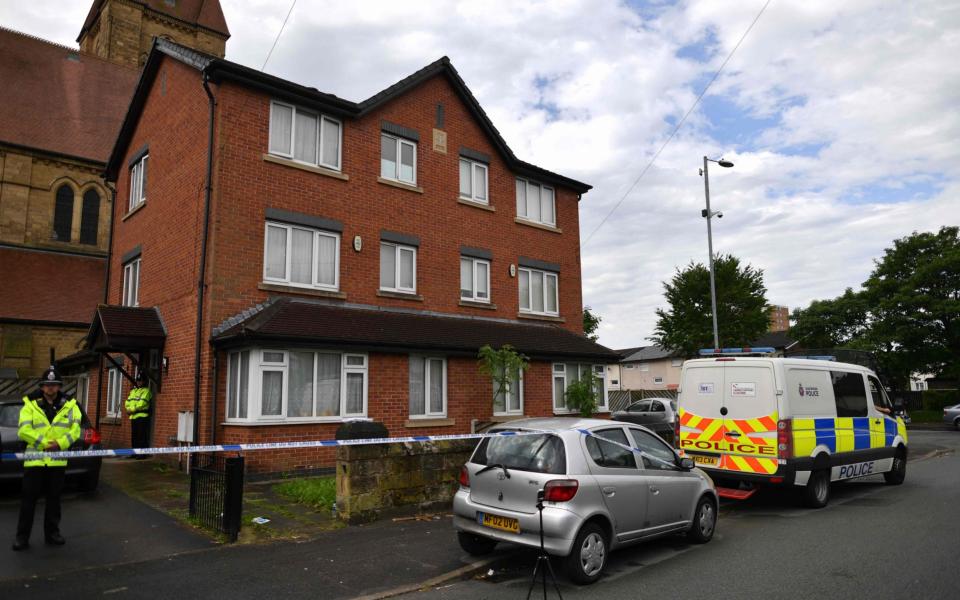 Policemen stand guard at a cordon around a house, which had been raided in a police operation in the early hours of the morning, at Cheetham Hill in Manchester - Credit: AFP