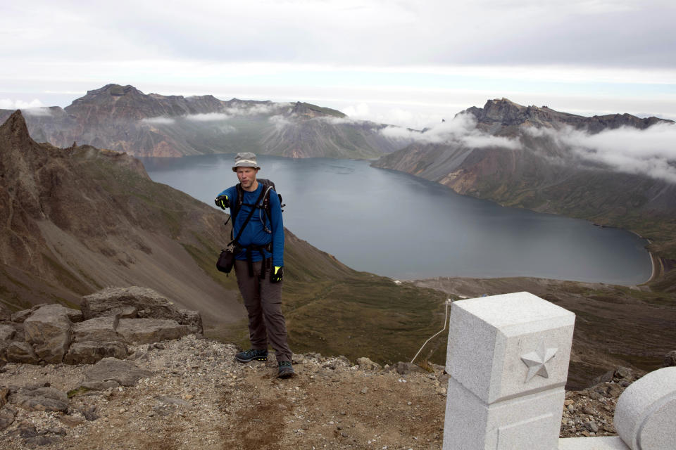 In this Saturday, Aug. 18,2018, photo, Tarjei Naess Skrede of Norway who is hiking with Roger Shepherd of Hike Korea stands near a view of the caldera and Lake Chon on Mount Paektu in North Korea. Hoping to open up a side of North Korea rarely seen by outsiders, Shepherd, a New Zealander who has extensive experience climbing the mountains of North and South Korea is leading the first group of foreign tourists allowed to trek off road and camp out under the stars on Mount Paektu, a huge volcano that straddles the border that separates China and North Korea. (AP Photo/Ng Han Guan)