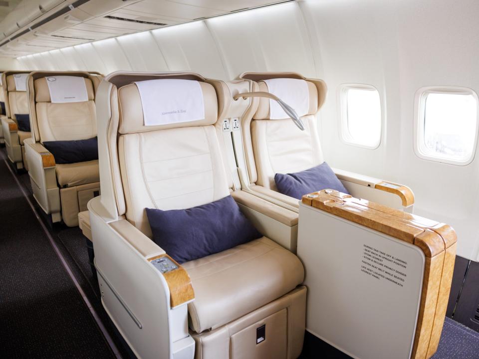 Rows of cream-colored seats onboard A&K's branded Boeing 757 all fully upright with blue pillows on the seat.