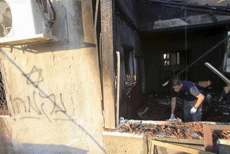 An Israeli police officer inspects a house that was badly damaged from a suspected attack by Jewish extremists on two houses at Kafr Duma village near the West Bank city of Nablus July 31, 2015. The Hebrew writing on the wall reads: "revenge". REUTERS/Abed Omar Qusini