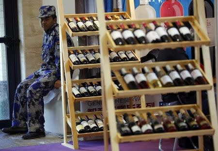 A security guard sits next to wine racks at Wine China Expo 2013 in Beijing September 24, 2013. REUTERS/Kim Kyung-Hoon