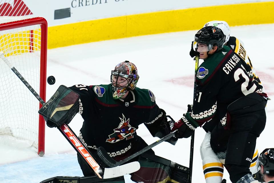 Arizona Coyotes goaltender Scott Wedgewood, left, makes a save on a shot by Boston Bruins left wing Brad Marchand, back right, as Coyotes left wing Loui Eriksson (21) defends during the first period of an NHL hockey game Friday, Jan. 28, 2022, in Glendale, Ariz. (AP Photo/Ross D. Franklin)