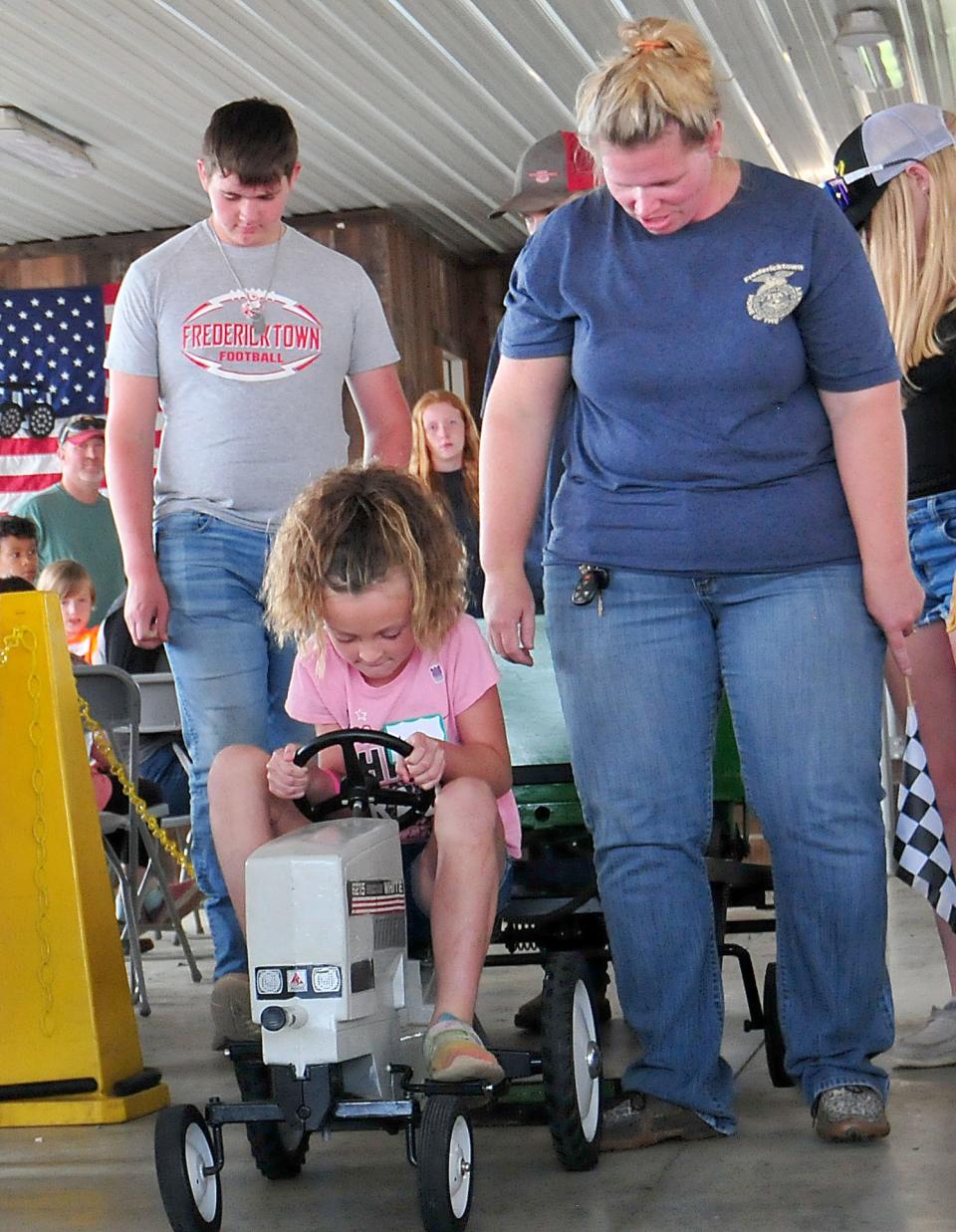 Charli Spoerr pulls a miniature sled on a pedal tractor during the Kiddie Tractor Pull in the Cheyenne Spidel Entertainment Pavilion Sunday at the fair.