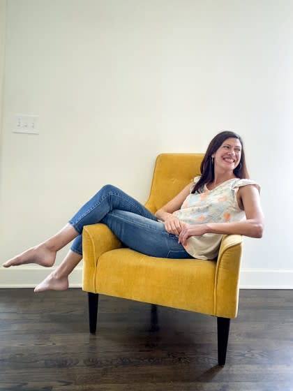 "Real World" star Julie Oliver in blue jeans and a floral top in a yellow chair, at her home outside Birmingham, Alabama.