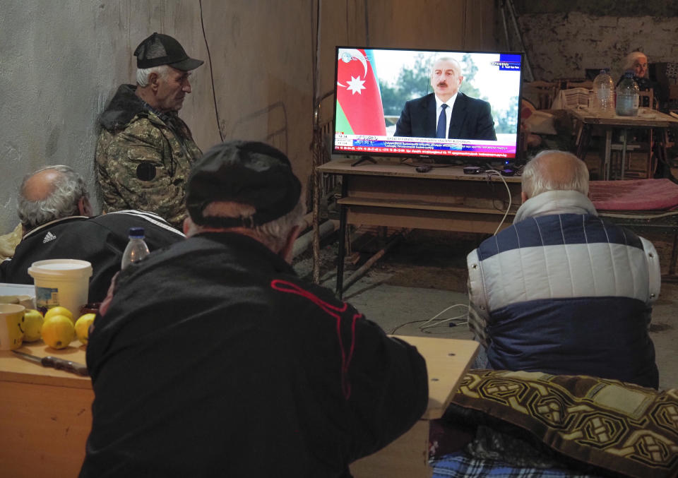 Armenians watch Azerbaijan's President Ilham Aliyev speaking on television as they take refuge in a bomb shelter in Stepanakert, the separatist region of Nagorno-Karabakh, Thursday, Oct. 22, 2020. Heavy fighting over Nagorno-Karabakh continued Thursday with Armenia and Azerbaijan trading blame for new attacks, hostilities that raised the threat of Turkey and Russia being drawn into the conflict. (AP Photo)