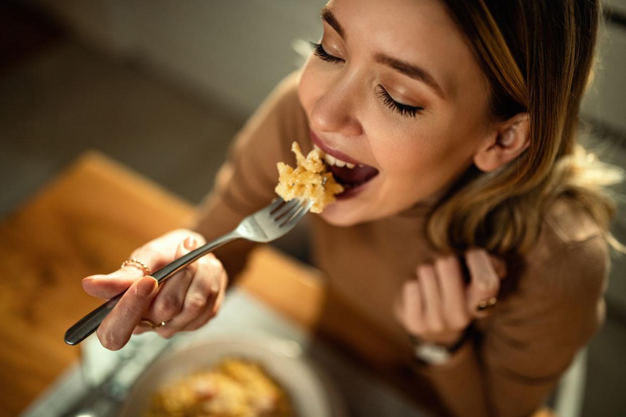 Close-up of happy woman eating pasta for dinner.