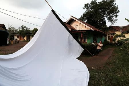 A worker erects a cinema screen before a wedding party in Bogor, Indonesia, February 18, 2017. REUTERS/Beawiharta/Files