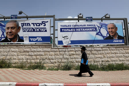 An ultra-Orthodox Jewish man walks past a Likud election campaign poster depicting Israeli Prime Minister Benjamin Netanyahu in Jerusalem April 7, 2019. REUTERS/Ammar Awad