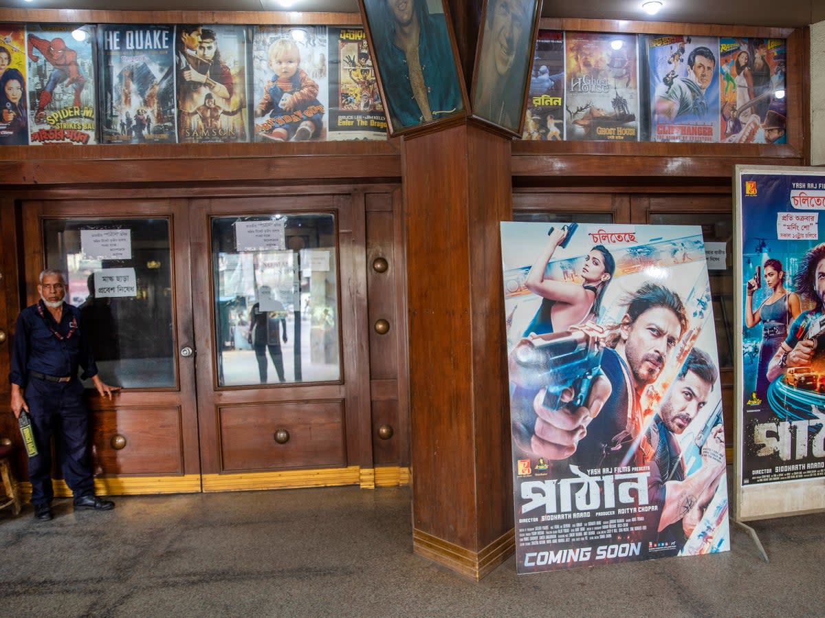 A Bangladeshi security guard stands next to  posters of the Indian Hindi-language movie 'Pathaan'  (EPA)