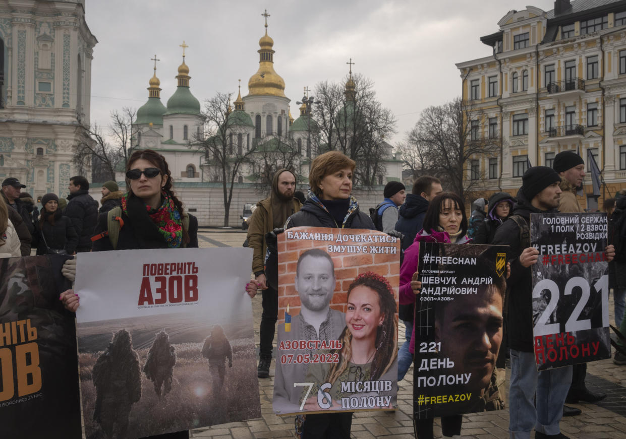 Relatives of soldiers from the Azov Regiment, who were captured by Russia in May after the fall of Mariupol, demand to free them at a flashmob action near St.Sophia Cathedral in Kyiv, Ukraine, Saturday, Dec. 24, 2022. Writing on posters reads "221 days in captivity". (AP Photo/Efrem Lukatsky)