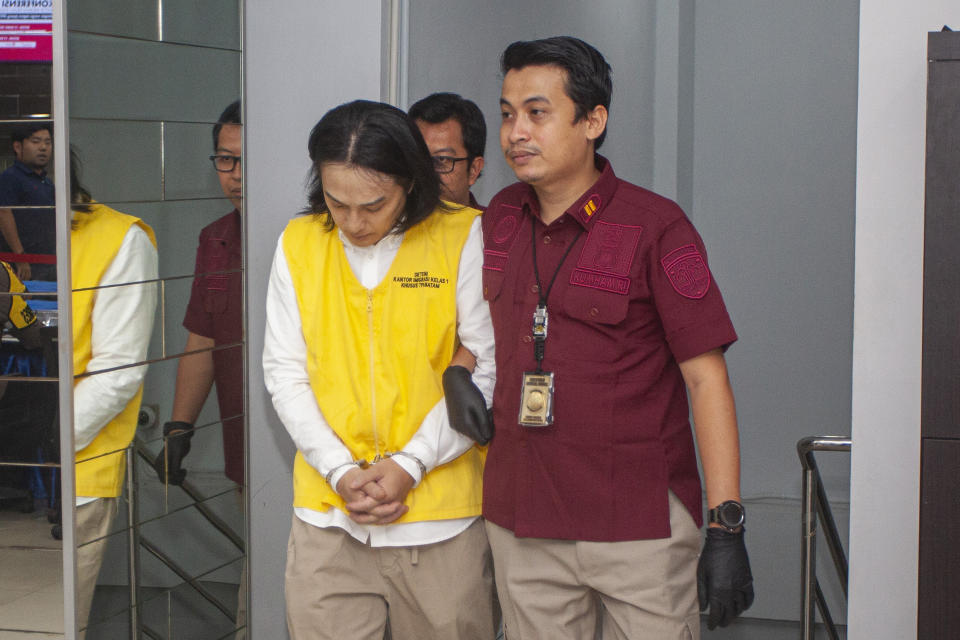 Indonesian Immigration officers escort Yusuke Yamazaki, left, a Japanese fugitive who is wanted for fraud in his home country, prior to his deportation in Batam, Indonesia, Tuesday, March 12, 2024. (AP Photo/Andaru Kz)