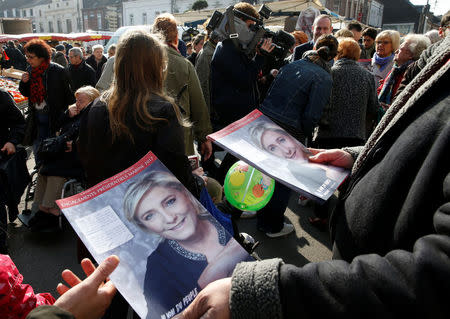 Supporters of French far right National Front political party leader Marine Le Pen distribute political leaflets as part of the 2017 French presidential election at a local market in Henin-Beaumont, France, April 7, 2017. REUTERS/Pascal Rossignol