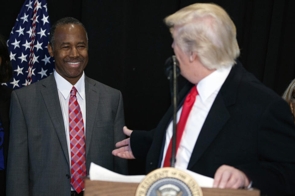 FILE - In this Feb. 21, 2017, file photo, then-Housing and Urban Development Secretary-designate Dr. Ben Carson, listens as President Donald Trump speaks after touring the National Museum of African American History and Culture in Washington. Carson’s story of growing up in a single-parent household and climbing out of poverty to become a world-renowned surgeon was once ubiquitous in Baltimore, where Carson made his name. But his role in the Trump Administration has added a complicated epilogue, leaving many who admired him feeling betrayed, unable to separate him from the politics of a president widely rejected by African Americans in Baltimore. (AP Photo/Evan Vucci, File)