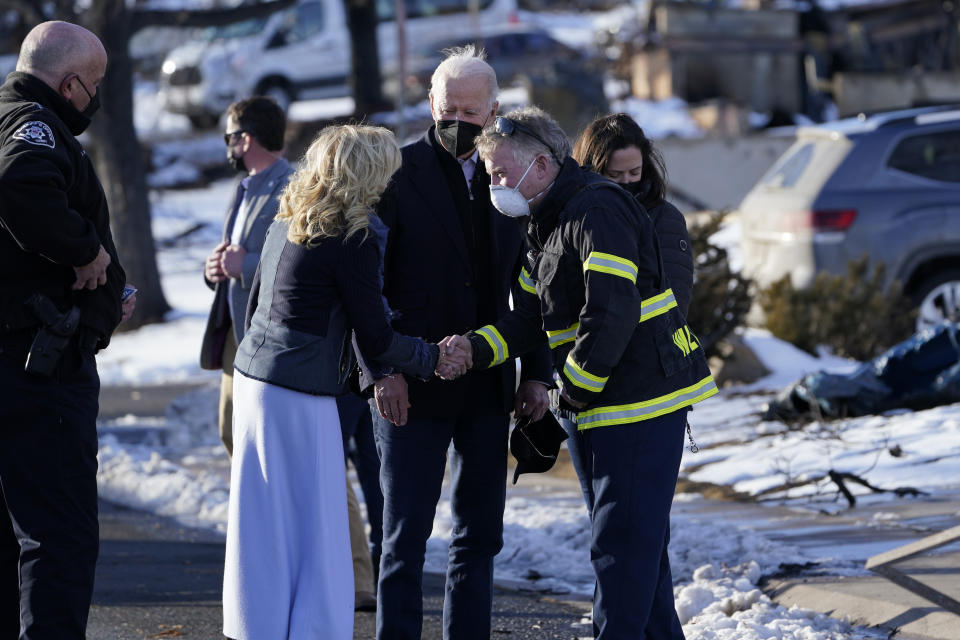 President Joe Biden and first lady Jill Biden greet a fire official as they tour a neighborhood in Louisville, Colo., Friday, Jan. 7, 2022, that was impacted by the recent wildfire. (AP Photo/Susan Walsh)