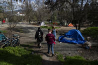 Cassy Leach, right, leads a group of volunteers to check on homeless people living in Baker Park on Thursday, March 21, 2024, in Grants Pass, Ore. (AP Photo/Jenny Kane)