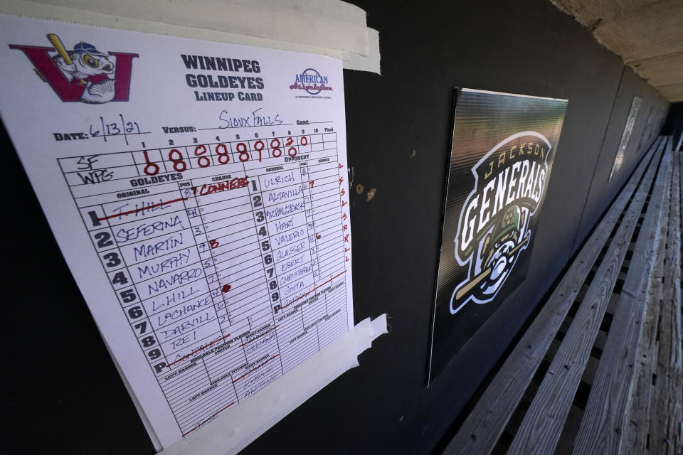 A lineup card for a Winnipeg Goldeyes game is taped to the dugout wall next to a sign for the Jackson Generals in The Ballpark at Jackson on Tuesday, June 22, 2021, in Jackson, Tenn. When Major League Baseball stripped 40 teams of their affiliation in a drastic shakeup of the minor leagues this winter, Jackson lost the Jackson Generals, the Double-A affiliate of the Arizona Diamondbacks. The Winnipeg Goldeyes are playing their home games in Jackson due to COVID-19 restrictions. (AP Photo/Mark Humphrey)