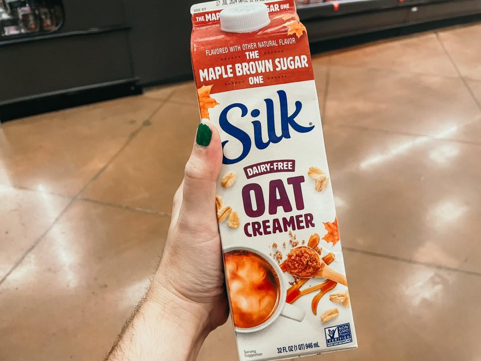 hand holding up a pint of silk oat milk creamer at target