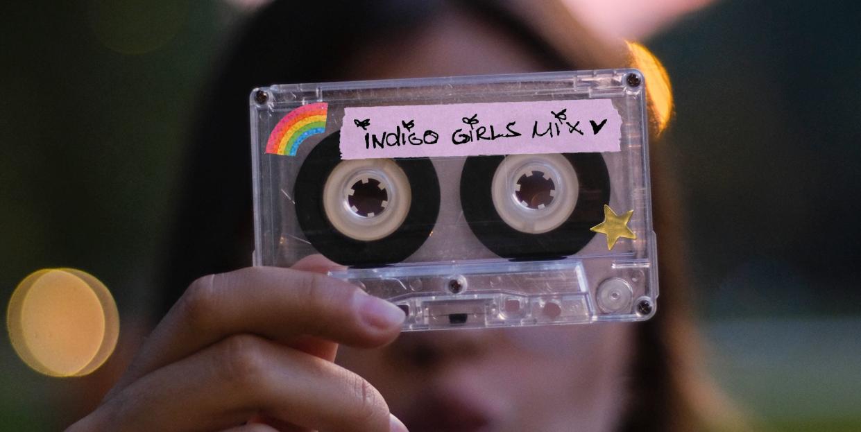 young teenage woman making funny faces and holding the audio cassette in front of her eyes in the park in summer