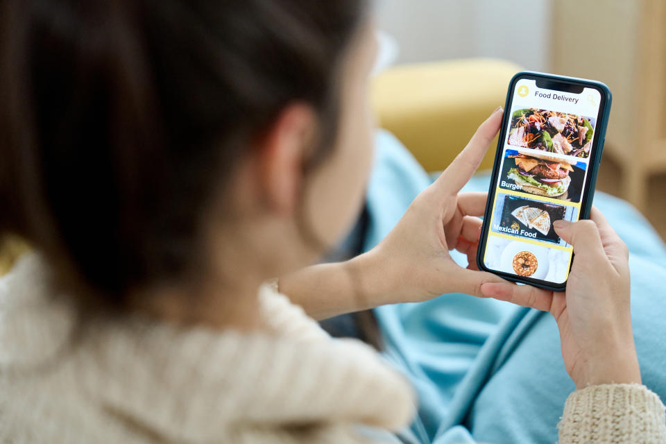 Person using a smartphone with a food delivery app open, displaying meal options