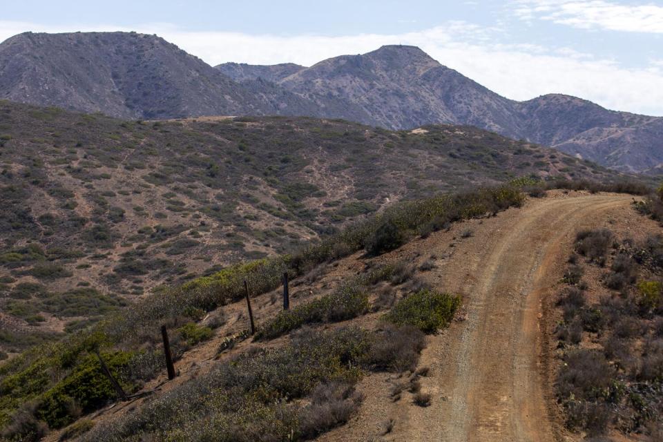 A dirt road runs through hilly terrain.