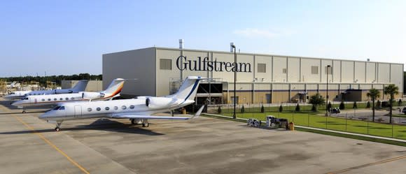 Gulfstream production facility with several business jets parked outside on a clear sunny day.