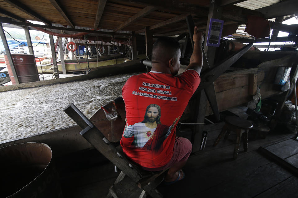 An illegal gold miner works on a dredging barge on the Madeira river, a tributary of the Amazon river, searching for gold, in Autazes, Amazonas state, Brazil, Thursday, Nov.25, 2021. Hundreds of mining barges have arrived during the past two weeks after rumors of gold spread, with environmentalists sounding the alarm about the unprecedented convergence of boats in the sensitive ecosystem. (AP Photo/Edmar Barros)