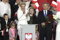 Incumbent President Andrzej Duda and his wife Agata Kornhauser-Duda smile after receiving flowers from supporters in Pultusk, Poland, Sunday, July 12, 2020. An exit poll in Poland's presidential runoff election shows a tight race that is too close to call between the conservative incumbent, Andrzej Duda, and the liberal Warsaw mayor, Rafal Trzaskowski.(AP Photo/Czarek Sokolowski)