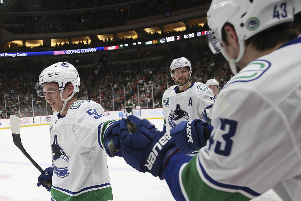 Vancouver Canucks' Troy Stecher, left, high-fives teammate Quinn Hughes after scoring a goal against the Minnesota Wild in the second period of an NHL hockey game Sunday, Jan. 12, 2020, in St. Paul, Minn. (AP Photo/Stacy Bengs)