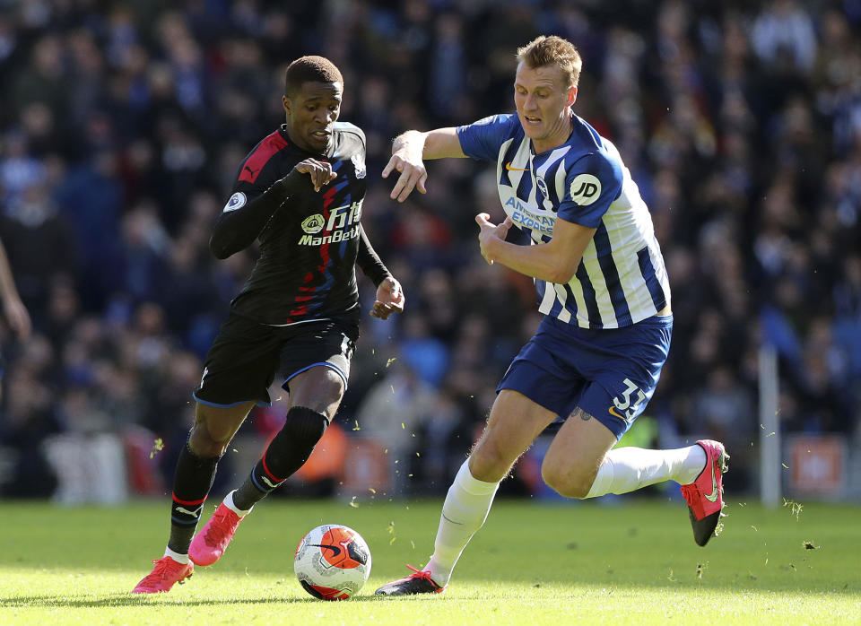 Dan Burn del Brighton (derecha) y Wilfried Zaha del Crystal Palace corren por el balón durante el partido de la Liga Premier inglesa, en Brighton, Inglaterra, el sábado 29 de febrero de 2020. (Gareth Fuller/PA via AP)