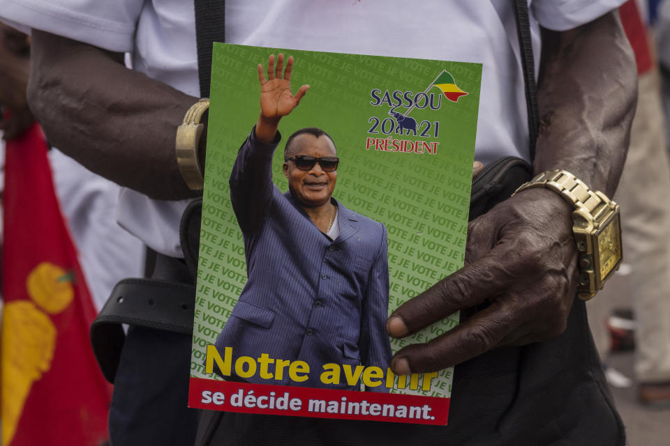 A supporter of President Denis Sassou N'Guesso holds his photo during the last rally of the presidential campaign in Brazzaville, Congo, Friday March 19, 2021. After 36 years in power, Republic of Congo's President Denis Sassou N’Guesso appears poised to extend his tenure as one of Africa's longest-serving leaders in the elections to be held Sunday amid opposition complaints of interference with their campaigns. (AP Photo/Zed Lebon)