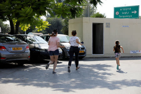 Israelis run for shelter as a siren sounds during a rocket attack near Yad Mordechai at the Israeli side of the Israel Gaza border July 14, 2018 REUTERS/Amir Cohen