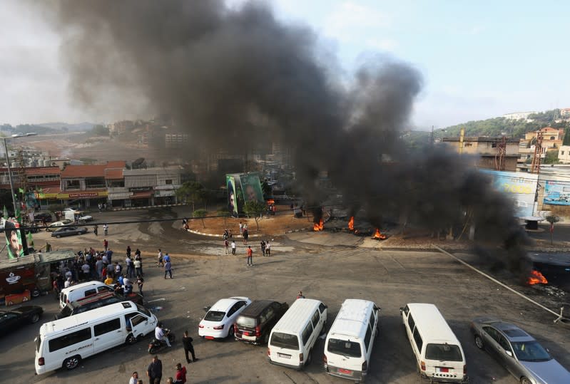 Demonstrators stand near burning tires blocking streets during a protest targeting the government over an economic crisis, in Nabatiyeh