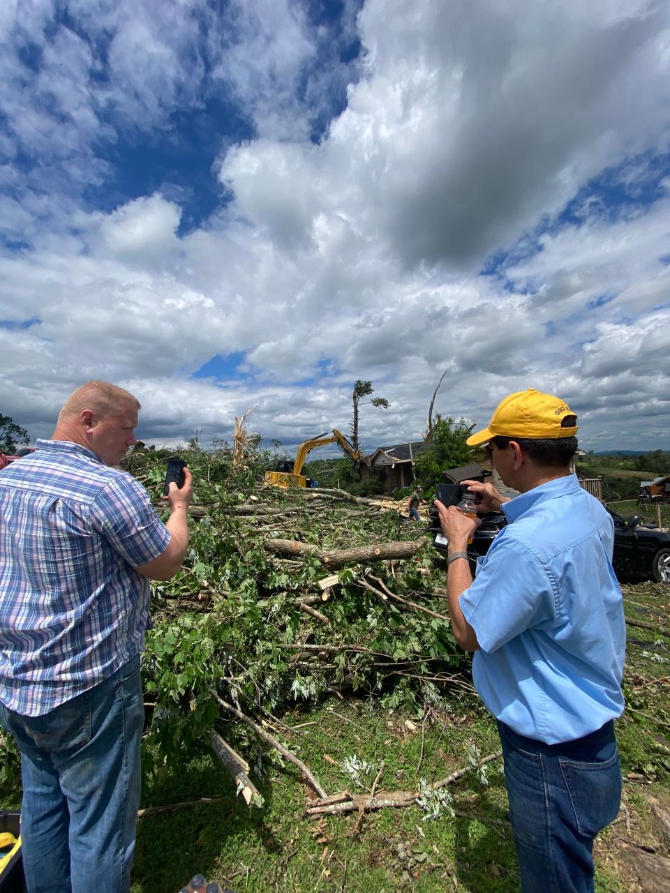 Sam Barnes, left and Donald Castillo, right, discuss the cleanup efforts Friday as a fallen tree is removed from the front of 1630 Blackburn Ln. in Columbia.