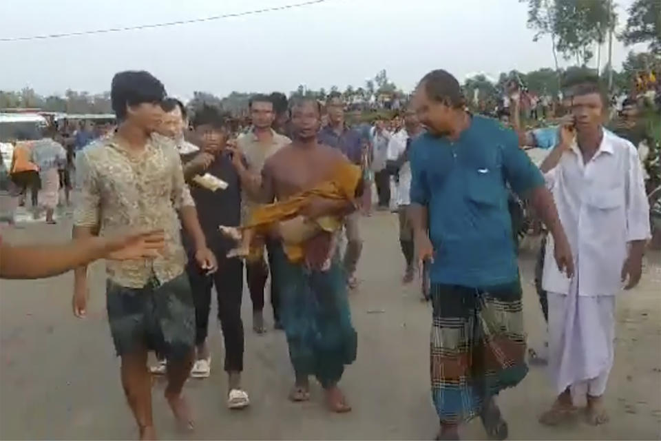 In this image made from a video, a man carries a dead body in Panchagarh, Bangladesh Sunday, Sept. 25, 2022. A boat carrying about 100 Hindu pilgrims capsized Sunday in a river in northern Bangladesh, police said. (AP Photo)