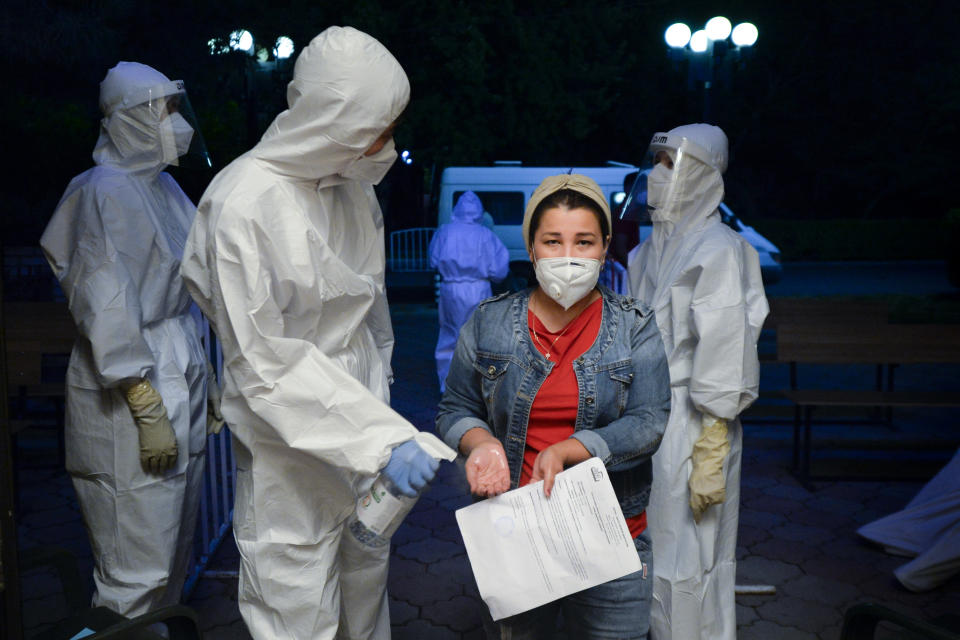 A medical worker disinfects hands of a patient who is suspected of having the coronavirus as she enters a hall of a restaurant that was converted into a night-time clinic in Bishkek, Kyrgyzstan, Wednesday, July 22, 2020. The restaurant in central Bishkek was converted into a night-time clinic an effort to support the impoverished country's health care system, struggling with the coronavirus outbreak. Doctors and nurses from other facilities work there and treat people between 8 p.m. and 8 a.m. (AP Photo/Vladimir Voronin)