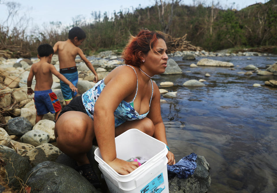 Maria Chiclano, who has no running water or power in her home, washes clothes with her sons in the Espiritu Santo river during heavy rains, more than two weeks after Hurricane Maria devastated Puerto Rico. (Photo: Mario Tama via Getty Images)