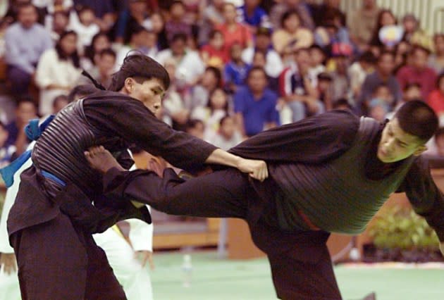 Abdul Kadir (R) lands a kick on Phu Sau Bui (L) of Vietnam to score a point at the Southeast Asian Games 1999. Kadir won the gold despite a small injury during the fight (AFP PHOTO)