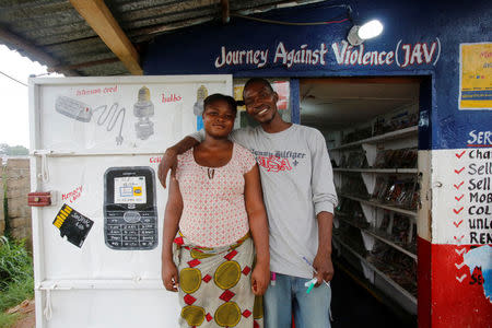 A former child soldier who received the Journey Against Violence (JAV) Program poses for a picture with he wife in front of his business centre in Mabaclay, Liberia, July 3, 2016. REUTERS/Thierry Gouegnon
