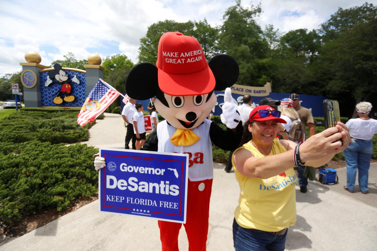 A person wearing a mouse costume takes selfies with supporters of Florida's Republican-backed 