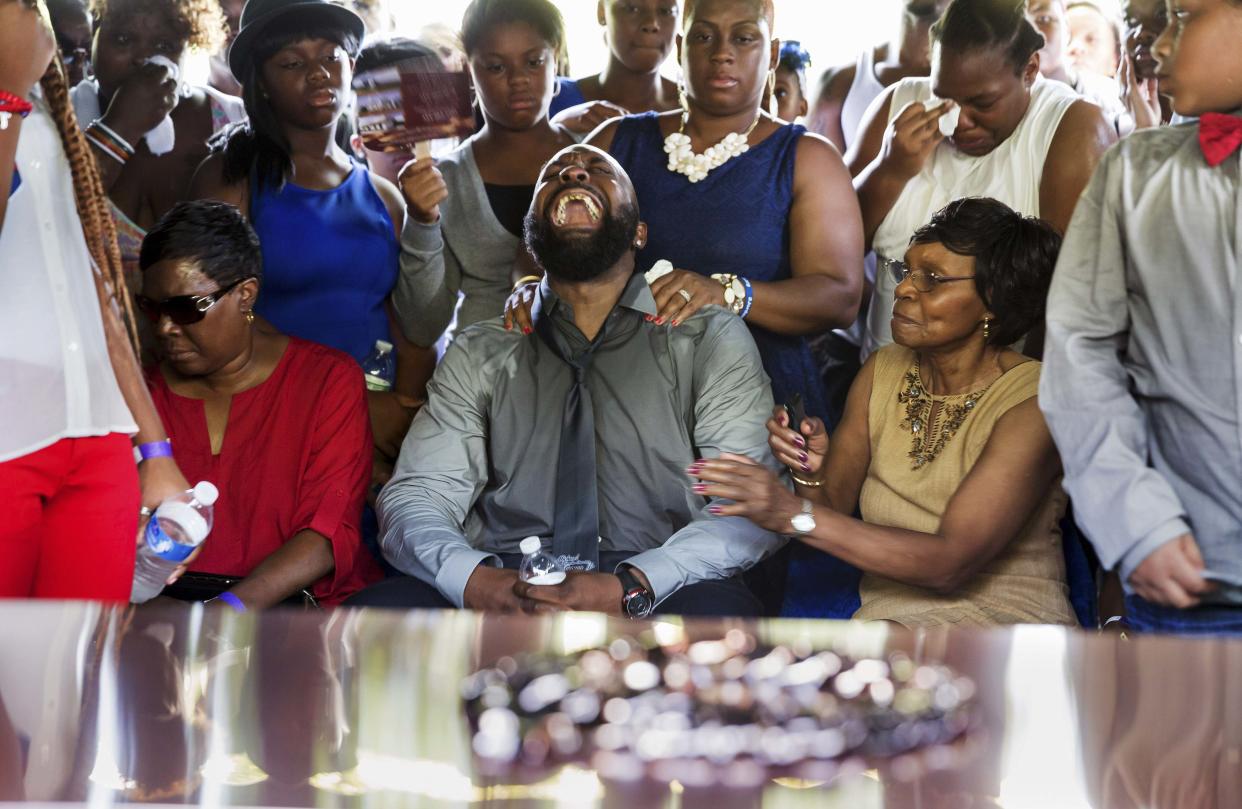 Michael Brown Sr., center, and Lesley McSpadden, left, react as their son’s casket is lowered into the ground in August 2014. The parents have filed a wrongful-death suit against the officer who shot Michael Brown Jr., the City of Ferguson, Mo. and the town’s former police chief. (Richard Perry/Reuters)