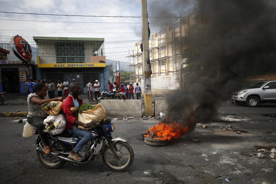 A motorcyclist drives past a burning barricade during a nationwide push to block streets and paralyze the country's economy as protesters press for President Jovenel Moise to give up power, in Port-au-Prince, Haiti, Monday, Sept. 30, 2019. Opposition leaders and supporters say they are angry about public corruption, spiraling inflation and a dwindling supply of gasoline that has forced many gas stations in the capital to close as suppliers demand the cash-strapped government pay them more than $100 million owed. (AP Photo/Rebecca Blackwell)