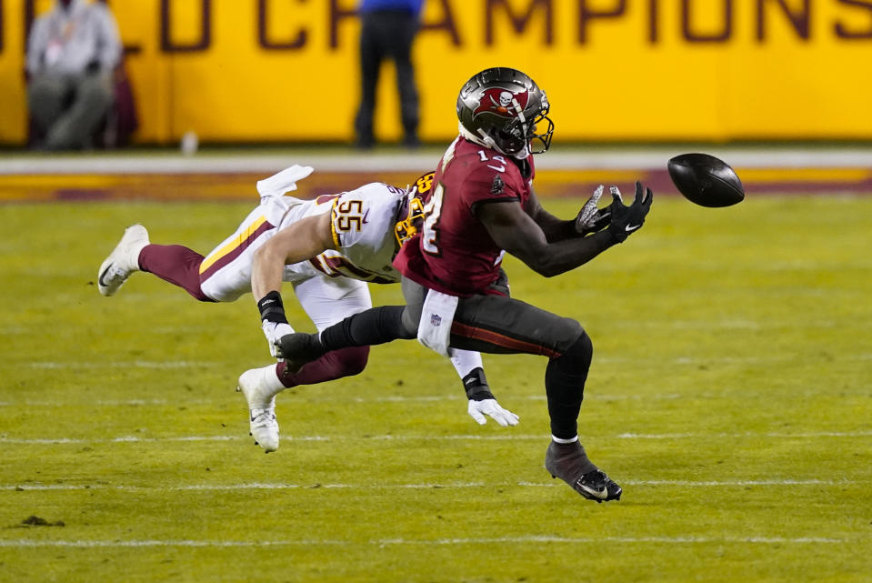 Tampa Bay Buccaneers wide receiver Chris Godwin (14) drops a pass as he goes up against Washington Football Team outside linebacker Cole Holcomb (55) during the second half of an NFL wild-card playoff football game, Saturday, Jan. 9, 2021, in Landover, Md. (AP Photo/Andrew Harnik)