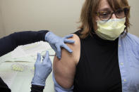 In this Dec. 18, 2020, photo provided by the Oregon Health & Science University, Christine Greco, a frontline employee who works at OHSU's drive-through COVID-19 testing site at Hillsboro Stadium, receives a Pfizer BioNtech COVID-19 vaccine injection in Hillsboro, Ore. As America's mass vaccination campaign gets underway and the virus surges, the nation is facing a moral dilemma as officials from California to New Jersey decide who gets the vaccine first. (Josh Andersen/OHSU via AP)