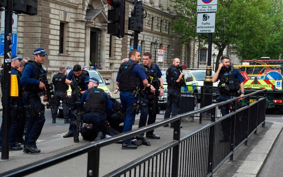 Firearms officiers from the British police detain a man on the ground on Whitehall near the Houses of Parliament  - Credit: AFP