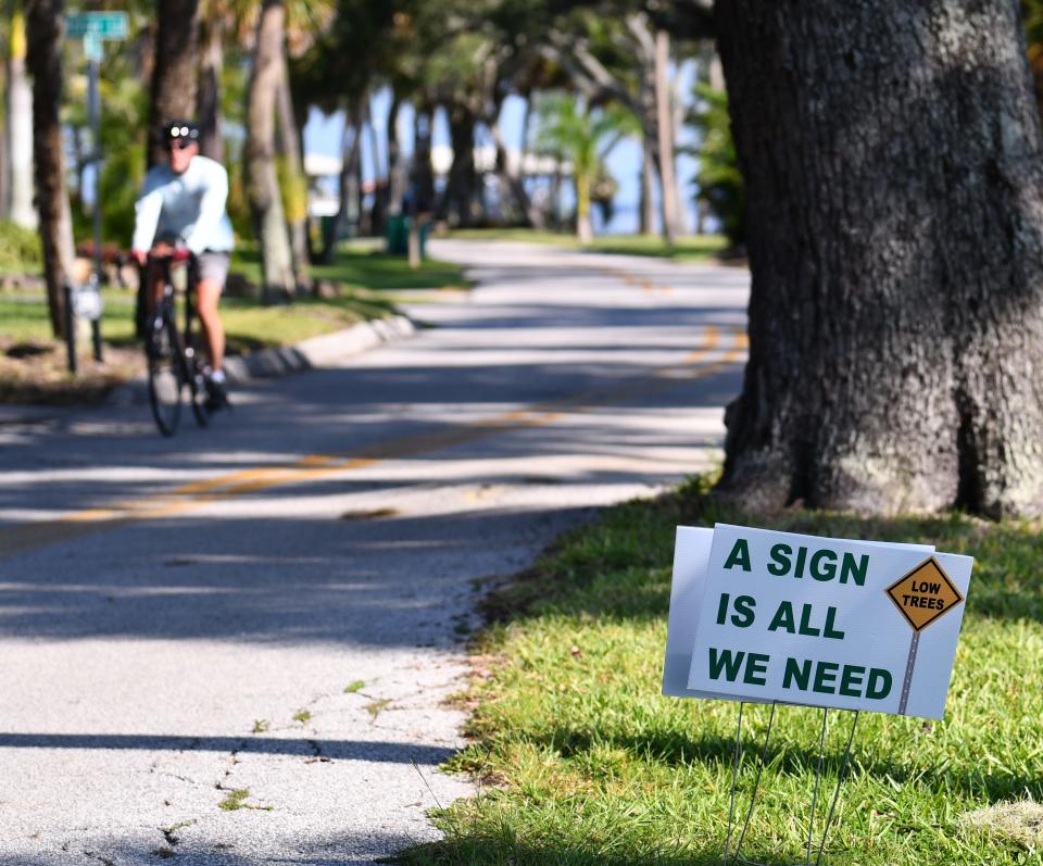 Residents of tree-lined Rockledge Drive have been putting up signs to lobby against the trimming of trees, saying warning signs for motorists is all that is needed.