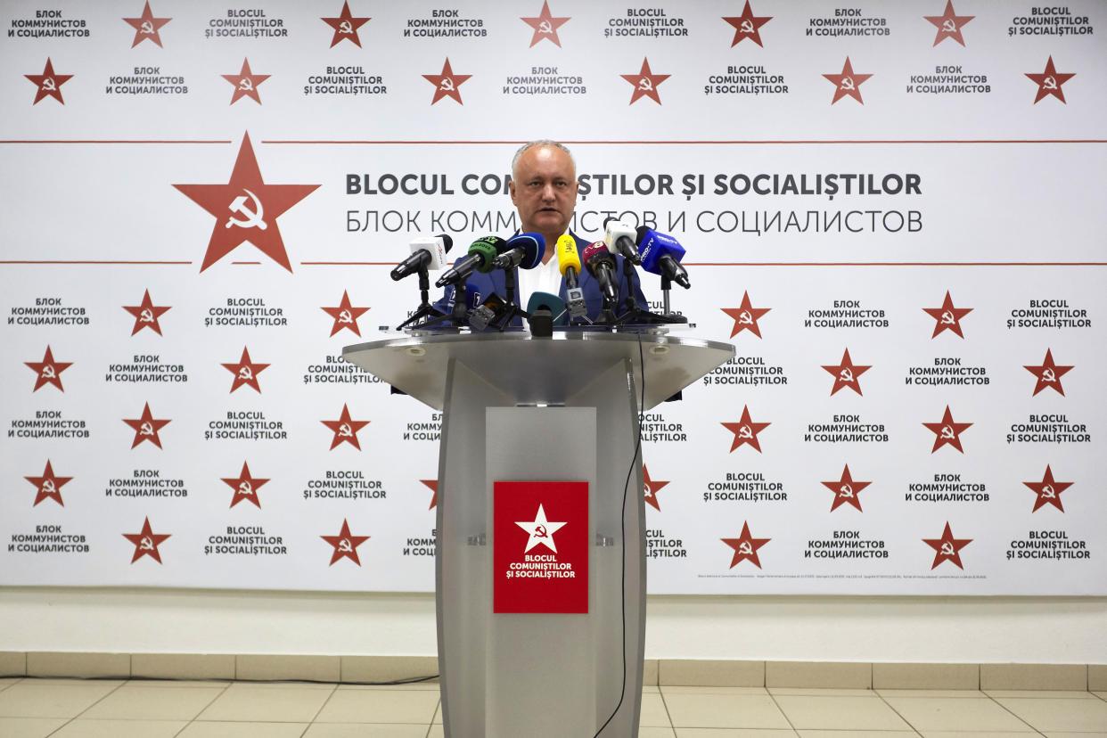 Igor Dodon, leader of Moldova's Bloc of Communists and Socialists, addresses the media, with his party's insignia, a hammer and sickle, repeated on the wall behind him.