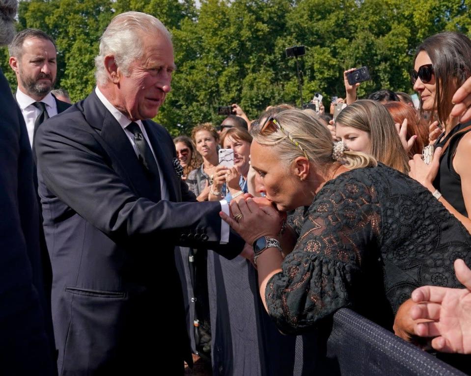 A well-wisher kisses the King’s hand during a walkabout outside Buckingham Palace on Thursday (Yui Mok/PA) (PA Wire)